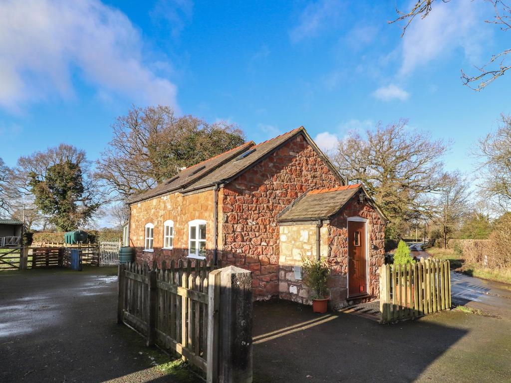 a small brick house with a wooden fence at The Laurels Barn in Oswestry