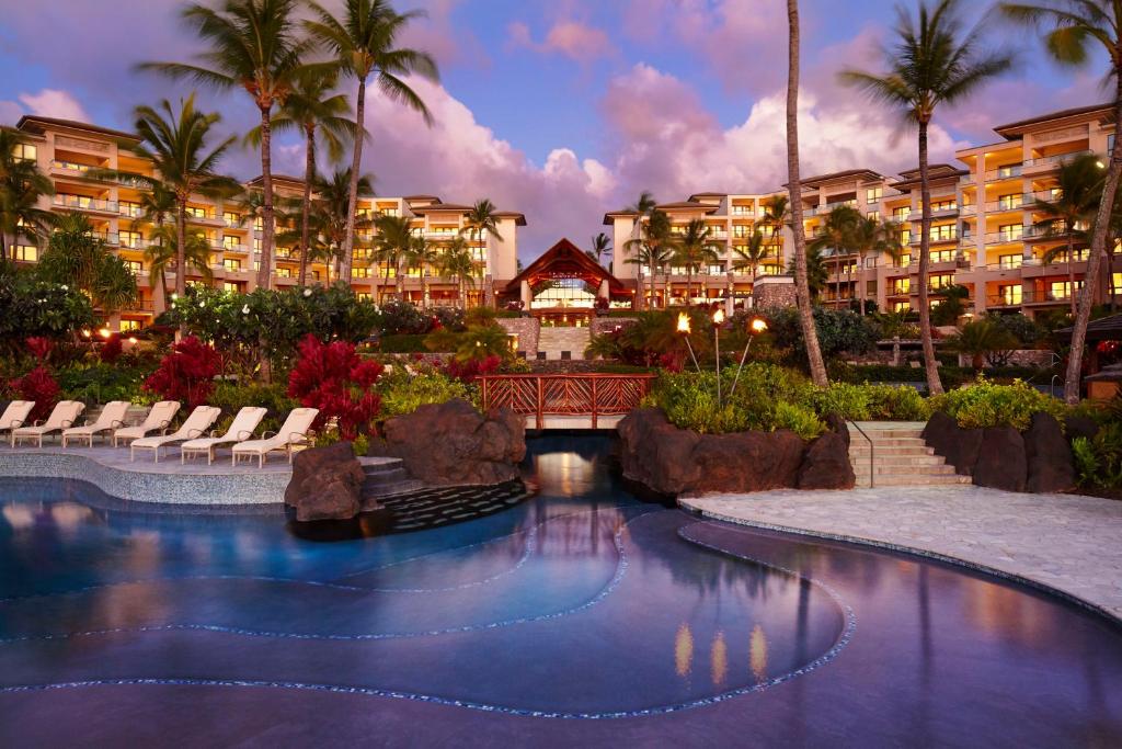 une piscine dans un complexe avec un pont et des palmiers dans l'établissement Montage Kapalua Bay, à Kapalua