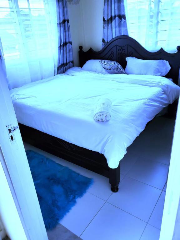 una camera da letto con letto, lenzuola e cuscini bianchi di Standard Gardens 1-2-3 bedrooms Apartment Kisumu a Kisumu