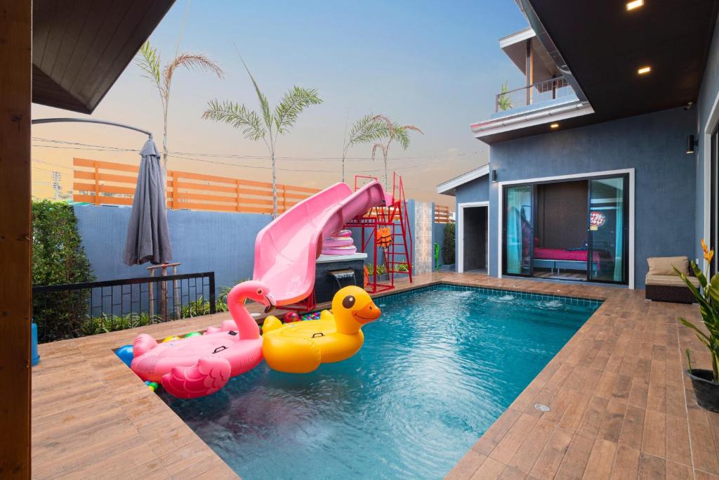 a swimming pool with a slide in a house at หมุนเงินหมุนทองพูลวิลล่า Mhunngen Mhunthong Pool Villa in Cha Am