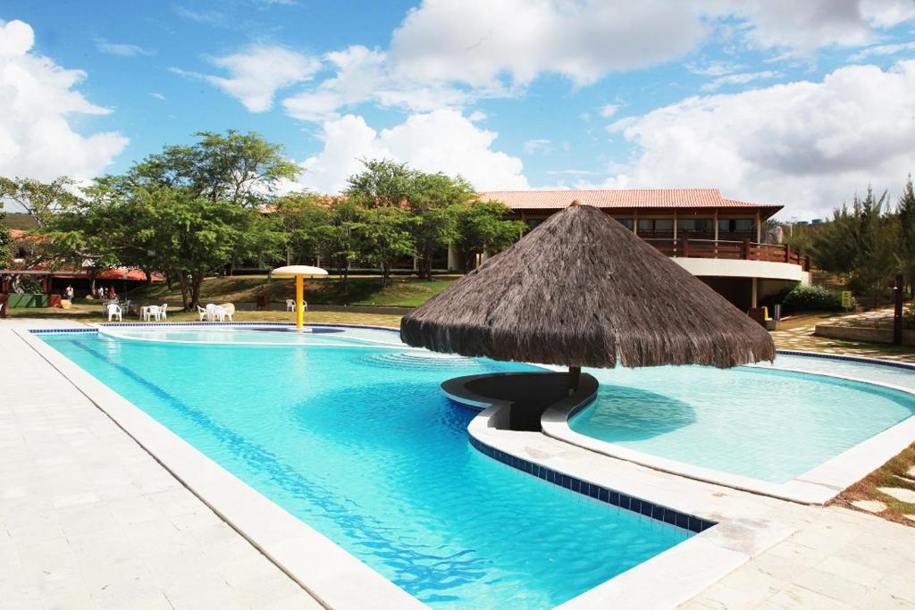 una gran piscina con sombrilla de paja en Flat Condomínio Fazenda Monte Castelo - Gravatá PE, en Recife