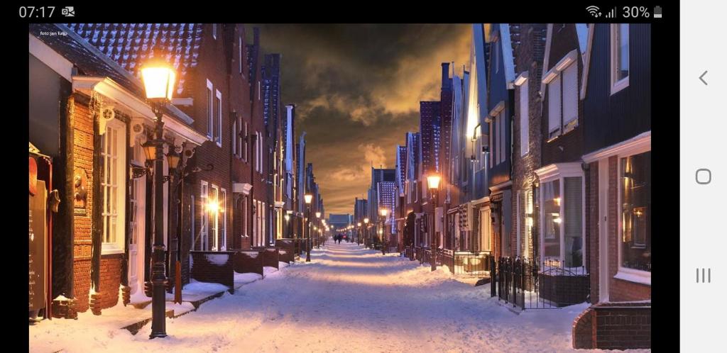 a snow covered street at night with buildings and street lights at B&B CaSandra in Volendam