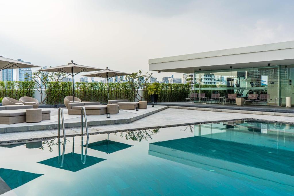 une piscine avec des chaises et des parasols dans un bâtiment dans l'établissement Oakwood Residence Sukhumvit Thonglor Bangkok, à Bangkok