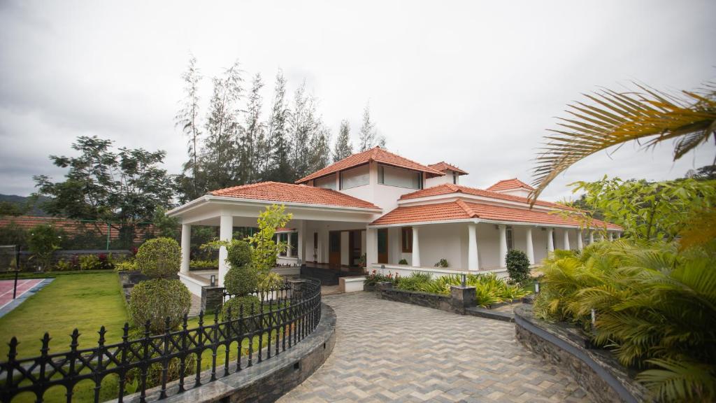 een wit huis met een hek ervoor bij SR Jungle Resort in Coimbatore