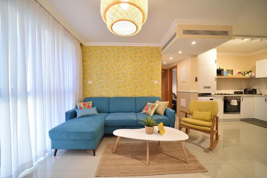 ein Wohnzimmer mit einem blauen Sofa und einem Tisch in der Unterkunft YalaRent Migdalor Boutique Hotel Apartments with Sea Views Tiberias in Tiberias