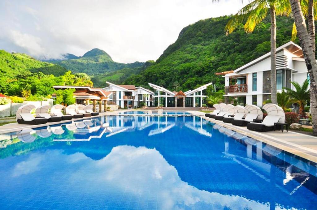 a pool at a resort with mountains in the background at Infinity Resort in Puerto Galera