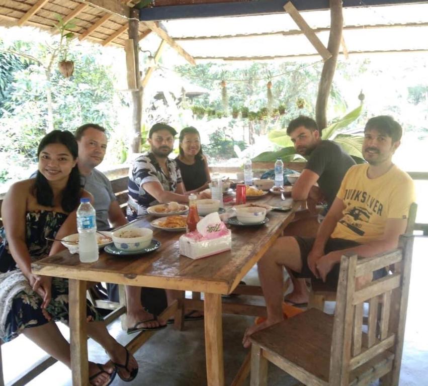 een groep mensen die rond een houten tafel zitten bij Phayam Garden View in Ko Phayam