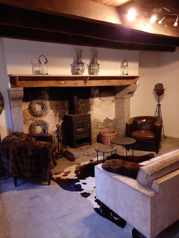 una sala de estar con sofás y una chimenea de piedra. en Luxe gîte met authentieke kamers in de Creuse, France, en Vallières