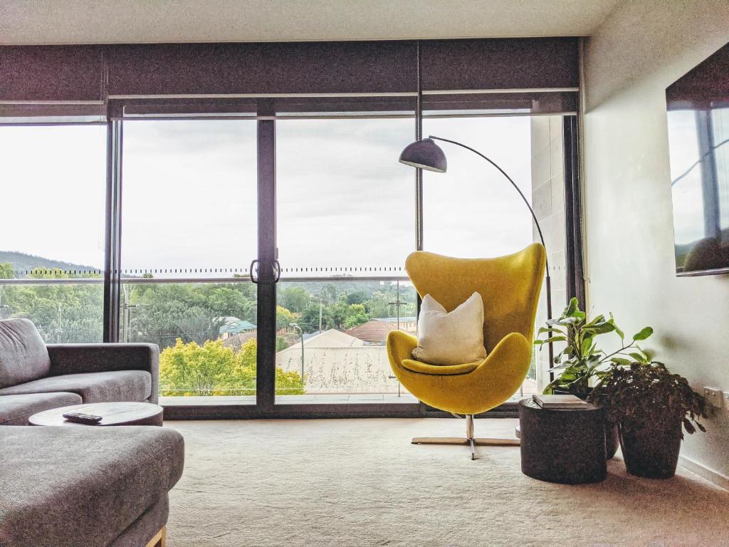 a living room with a yellow chair and a lamp at The Botanical 301 in Albury