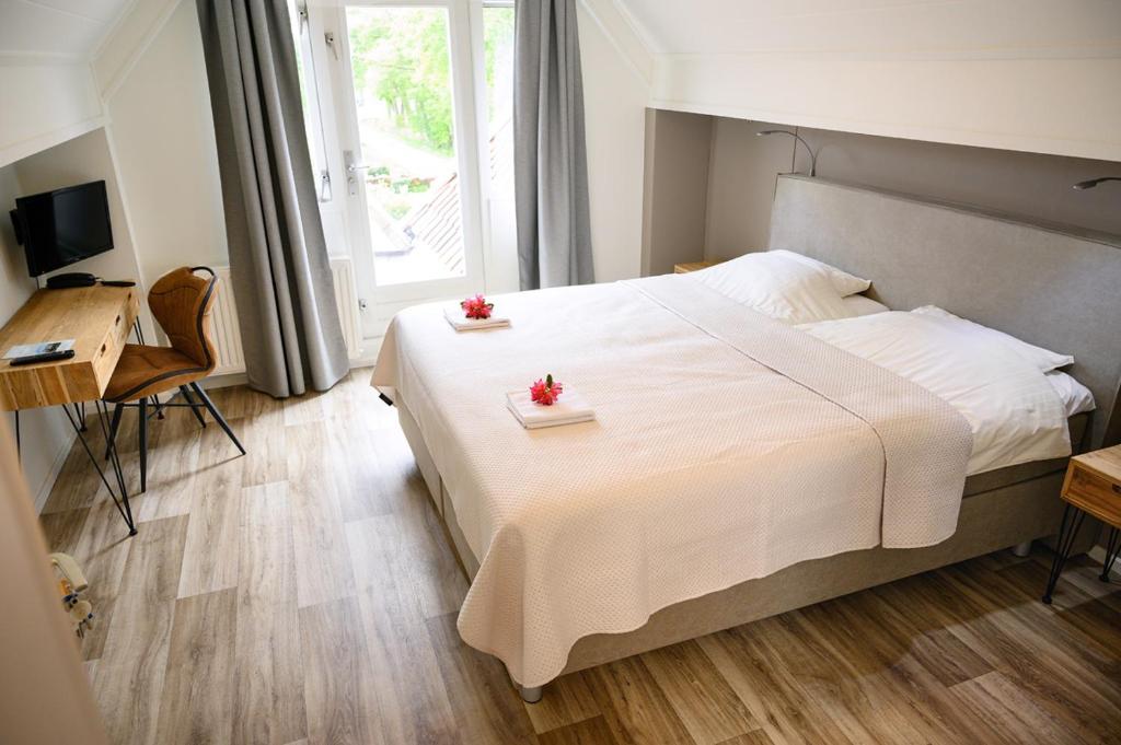 a bedroom with a large white bed with two flowers on it at Hotel Jachtlust in Borne