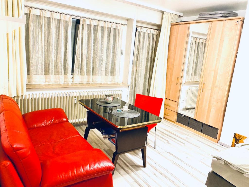 ein Wohnzimmer mit einem roten Sofa, einem Schreibtisch und einem Stuhl in der Unterkunft Klein aber dein... in Pforzheim