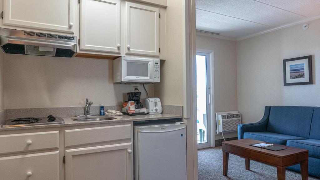a kitchen with white cabinets and a blue couch in a room at Comfort Inn Ocean City Boardwalk in Ocean City