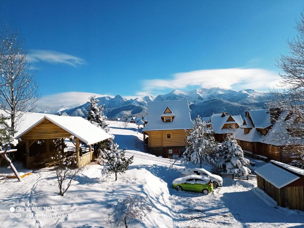 une maison enneigée avec une voiture garée dans la neige dans l'établissement Noclegi u Gabrysi, à Kościelisko