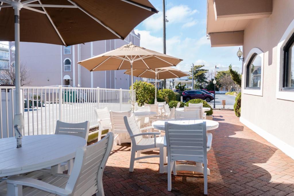 a patio with white tables and chairs and umbrellas at Comfort Inn Ocean City Boardwalk in Ocean City