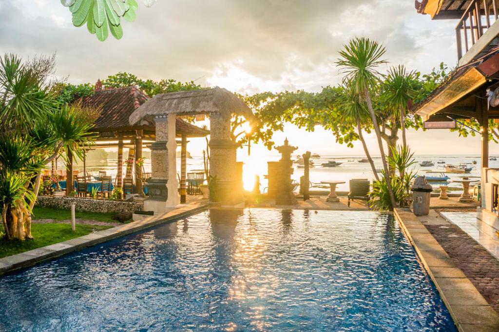 a swimming pool in a resort with the ocean in the background at Bungalow No 7 in Nusa Lembongan