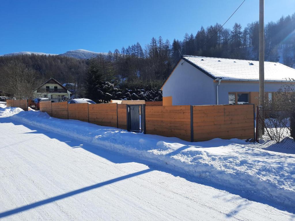 a snow covered yard with a fence and a house at Pod Sedlem in Loučná nad Desnou