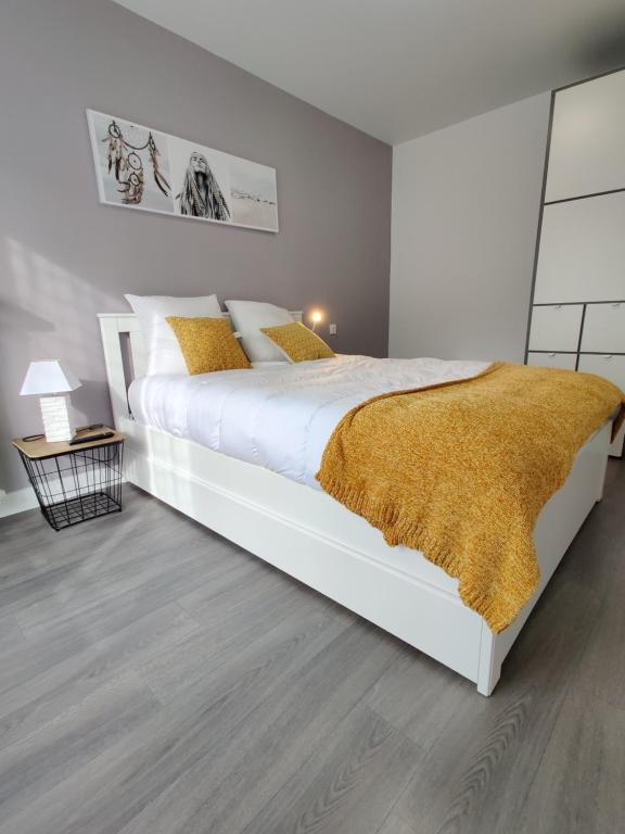 - une chambre avec un grand lit blanc et une couverture jaune dans l'établissement LE FOUCAULD-GoodCaen, à Caen