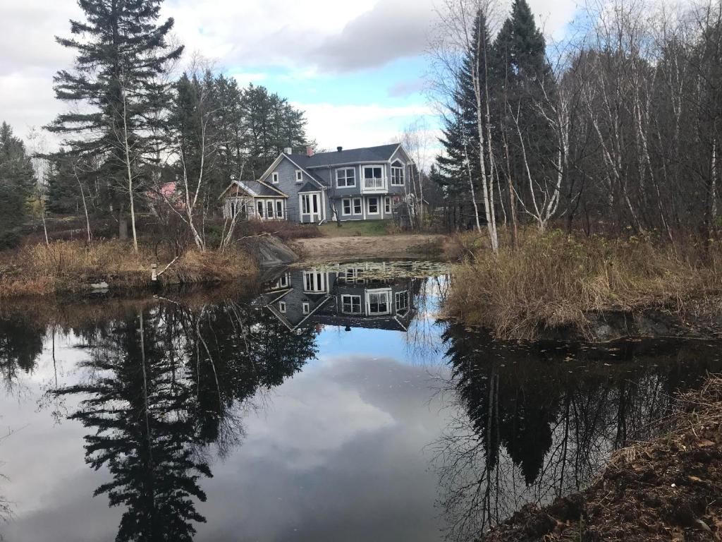 a large house sitting on the side of a lake at Vieille École du Rang 3 in Saint-Henri-de-Taillon