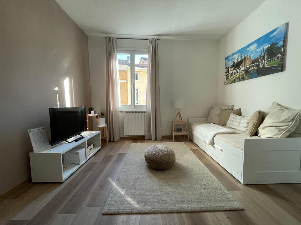 ein Wohnzimmer mit einem weißen Sofa und einem TV in der Unterkunft CIVICO 57 Al Santo - PADOVA in Padua