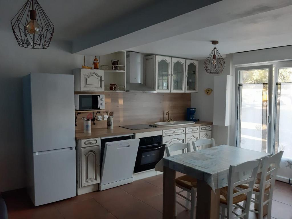 una cocina con electrodomésticos blancos y una mesa con sillas. en Au cœur de Pornic en Pornic