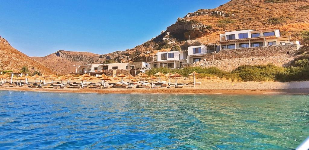 Spathi Beach Suites Kea في Spathi : فندق على شاطئ فيه كراسي ومظلات