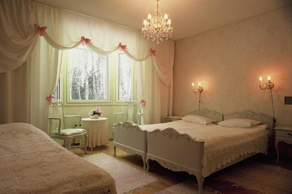 1 dormitorio con 2 camas y lámpara de araña en Hotelli Kultainen Joutsen, en Kuusamo
