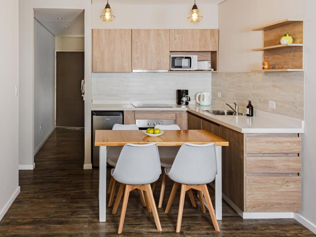 a kitchen with a wooden table and white chairs at LEVEL Suites una propuesta diferente en el centro de Bahía in Bahía Blanca