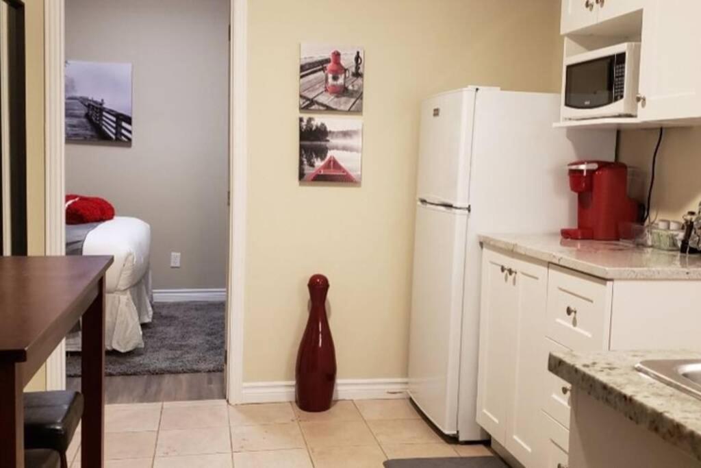 a kitchen with a refrigerator and a room with a bed at Cozy Sweet #19. By Amazing Property Rentals in Gatineau