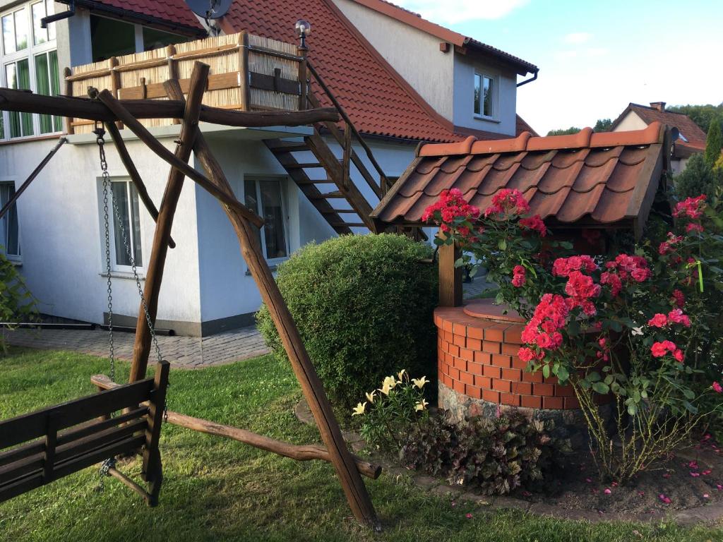 Agroturystyka Niezapominajka في كوسيفو: حديقة فيها كرسي وزهور امام المنزل