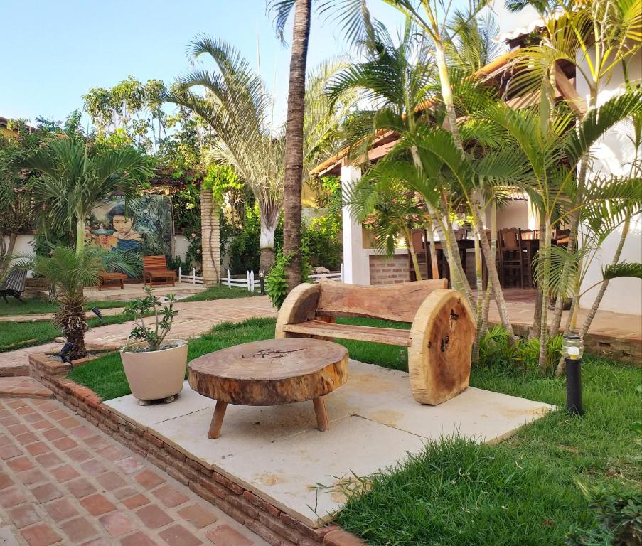 a park with a bench and a table and palm trees at Pousada Peixe D'Ouro in Jericoacoara