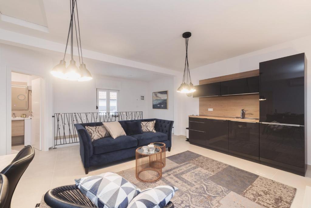Apartment Ema في زادار: غرفة معيشة مع أريكة زرقاء وتلفزيون