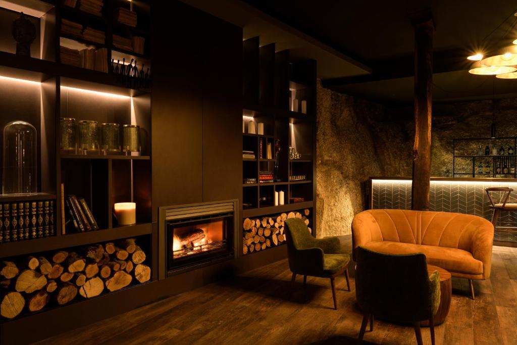 コビリャンにあるPena D'Água Boutique Hotel & Villasのリビングルーム(暖炉、椅子付)