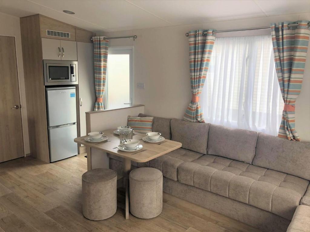 a living room with a couch and a table at Willow Superior Holiday Home in Chapel Saint Leonards