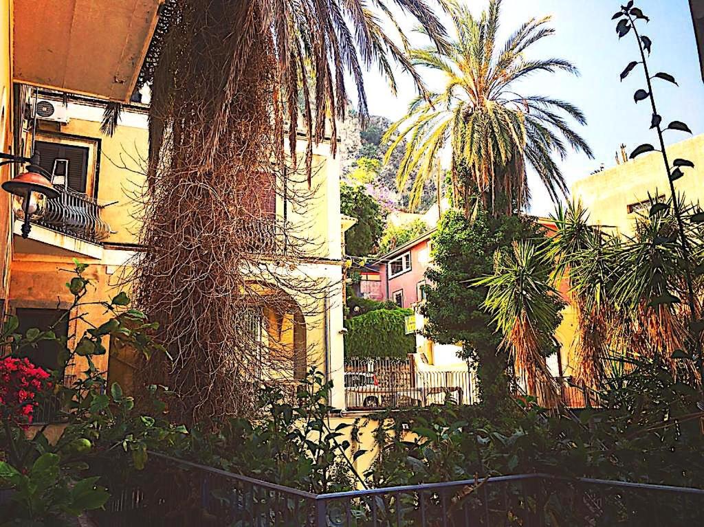 a palm tree in front of a building at Archè Apartment in Taormina