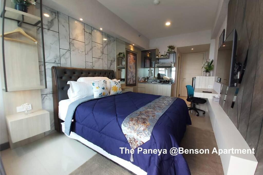 a bedroom with a large bed with a blue blanket at The Paneya @Benson Apartment in Surabaya