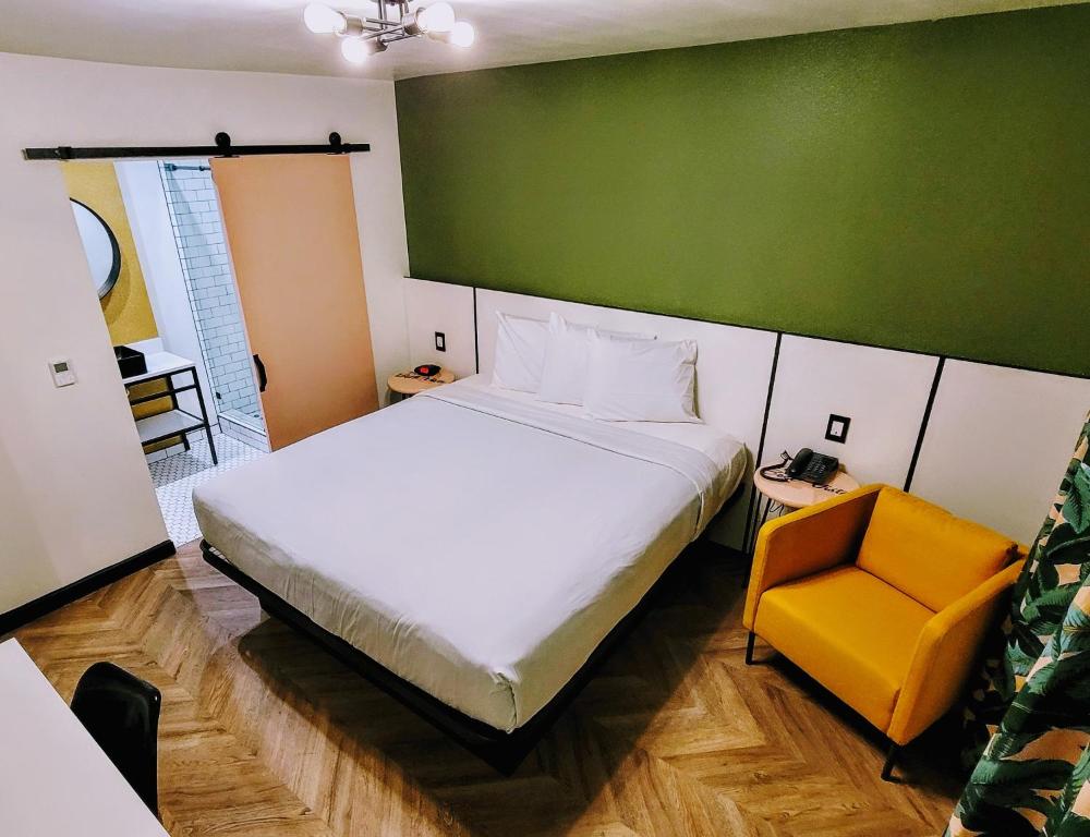 a bedroom with a large bed and a yellow chair at The Bell Vista in Burbank