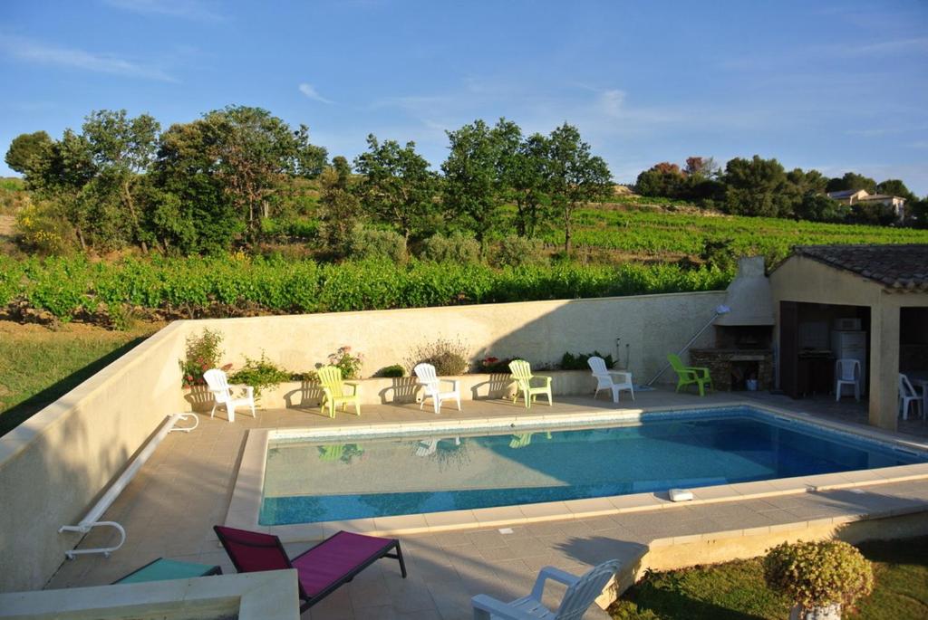 a swimming pool with chairs and a table next to at CHAMBRES D&#39;HÔTES CLIMATISÉES avec CUISINE d&#39;ÉTÉ &quot;VILLA GOUR du PEYROL&quot; in Buisson