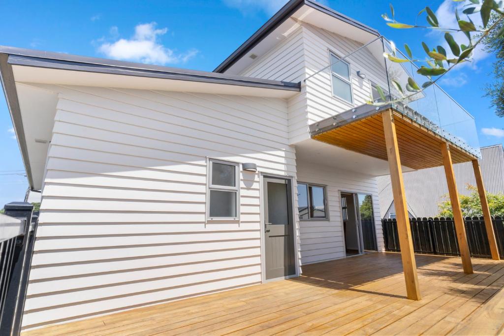 a white house with a wooden deck at Picturesque Papamoa - Papamoa Holiday Home in Papamoa