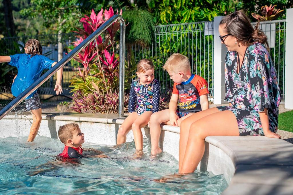 una mujer y niños jugando en una piscina en BIG4 Whitsundays Tropical Eco Resort en Airlie Beach