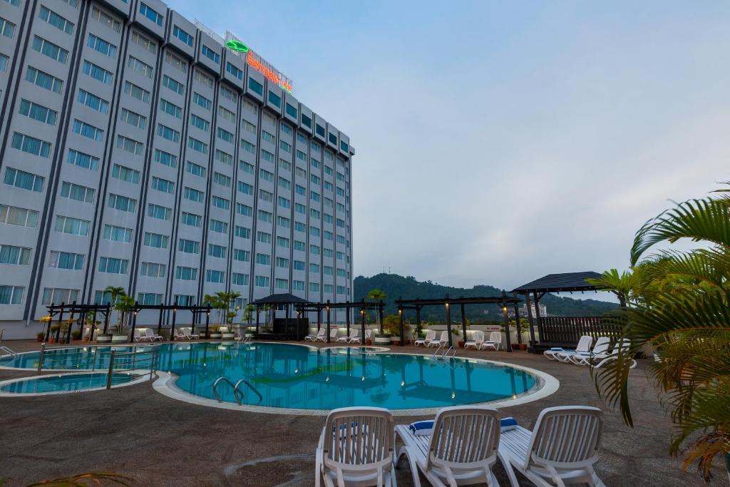 a hotel with a swimming pool in front of a building at Bayview Hotel Langkawi in Kuah