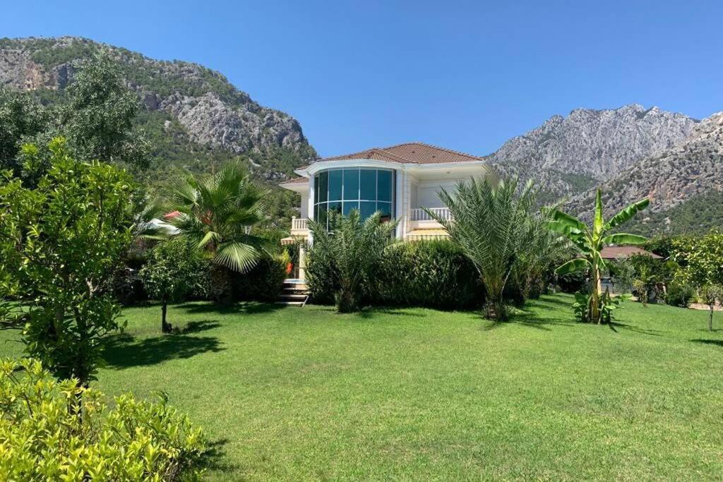 a house on a lawn with mountains in the background at Luxury Villa for rent in Kemer, Göynük Antalya in Antalya