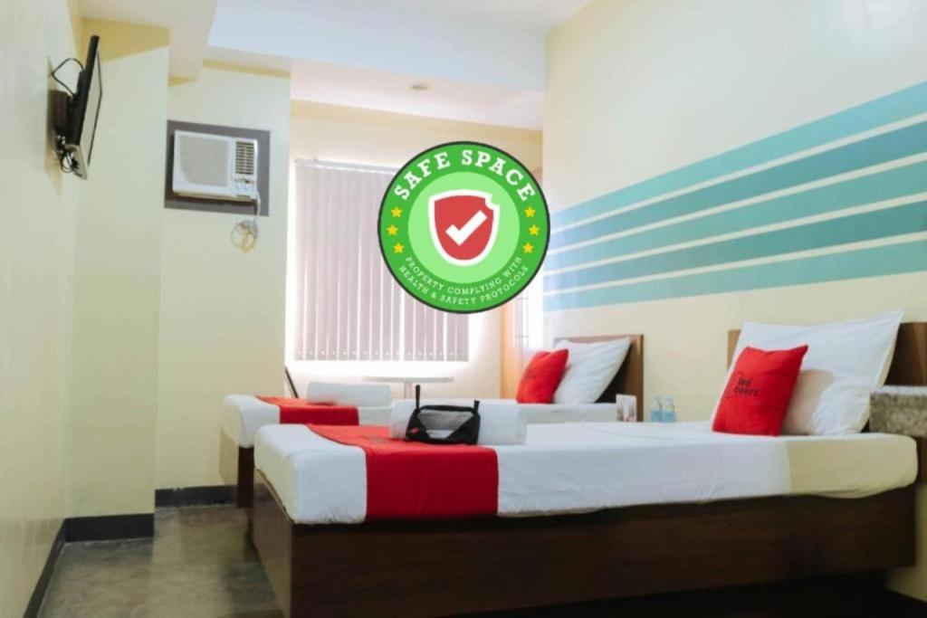 two beds in a room with a sign on the wall at RedDoorz @ MJ Cuenco Avenue Cebu in Cebu City