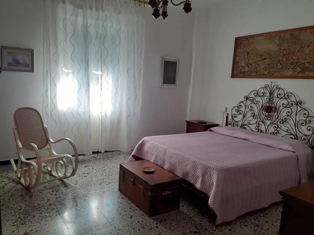 Un dormitorio con una cama, una silla y una ventana en La casa di Mirella, en Ne