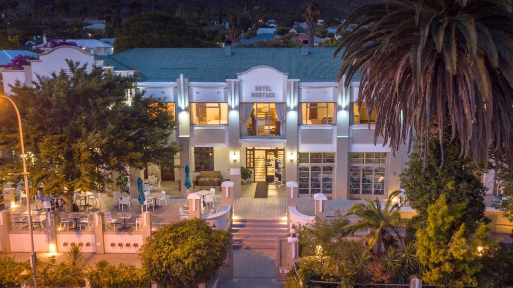 a white building with a palm tree in front of it at Montagu Country Hotel in Montagu