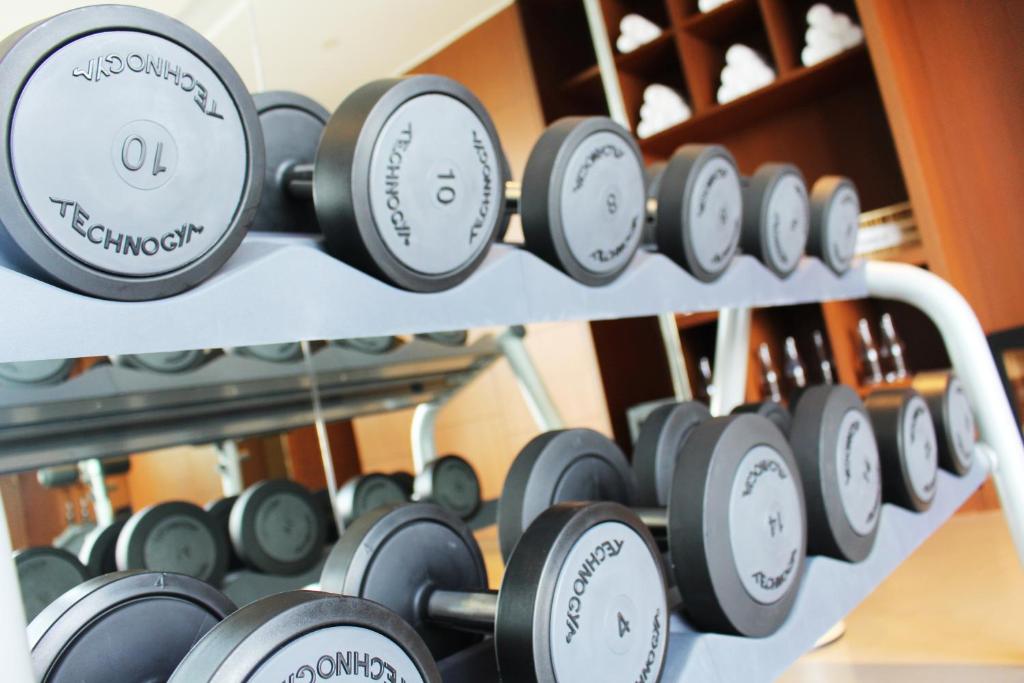 A close-up of a Technogym dumbbell rack set against mirrored shelving.