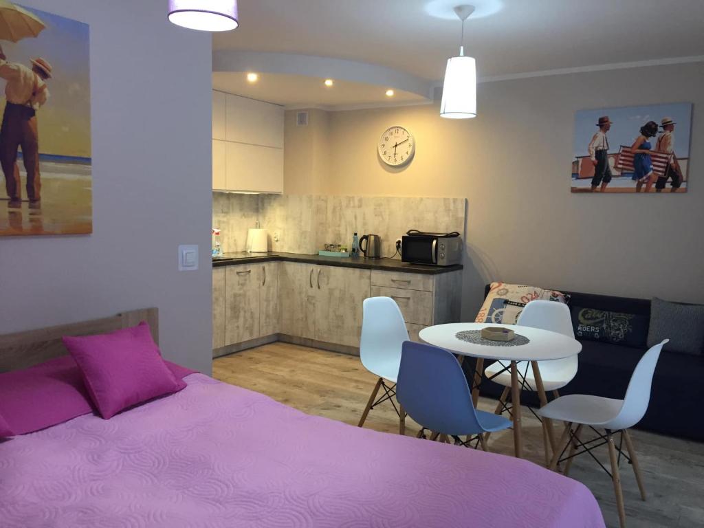 1 dormitorio con cama rosa, mesa y sillas en Apartament Osiemnastka, nad morzem, najwygodniejszy dla par, jednopokojowy typu studio, en Darłowo