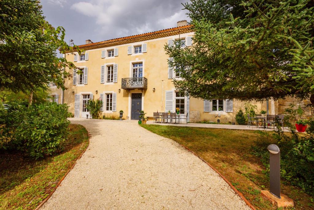 un percorso che conduce a un grande edificio giallo di Le Castel Pierre - Maison privée 4 étoiles - 18 personnes a Lagraulet-du-Gers