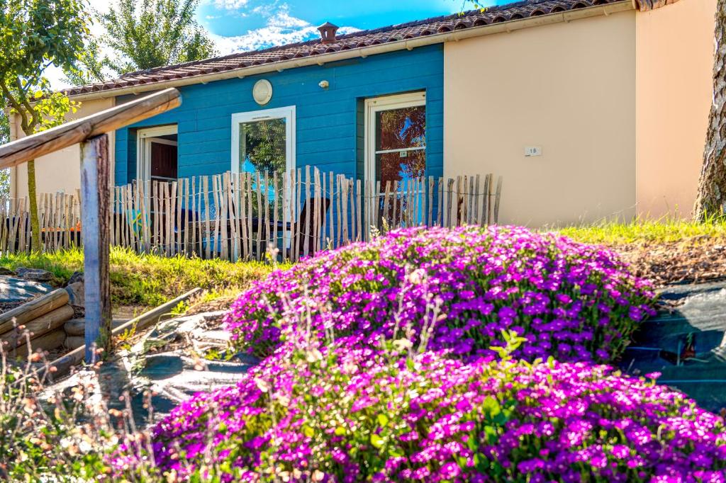 Uma casa azul com flores cor-de-rosa à frente. em Olydea Les Epesses em Les Épesses