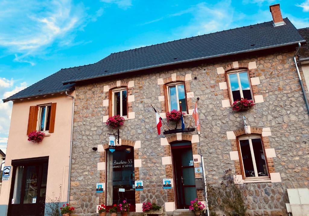 un edificio de piedra con flores en las ventanas en La Bouchère 33, en Meuzac