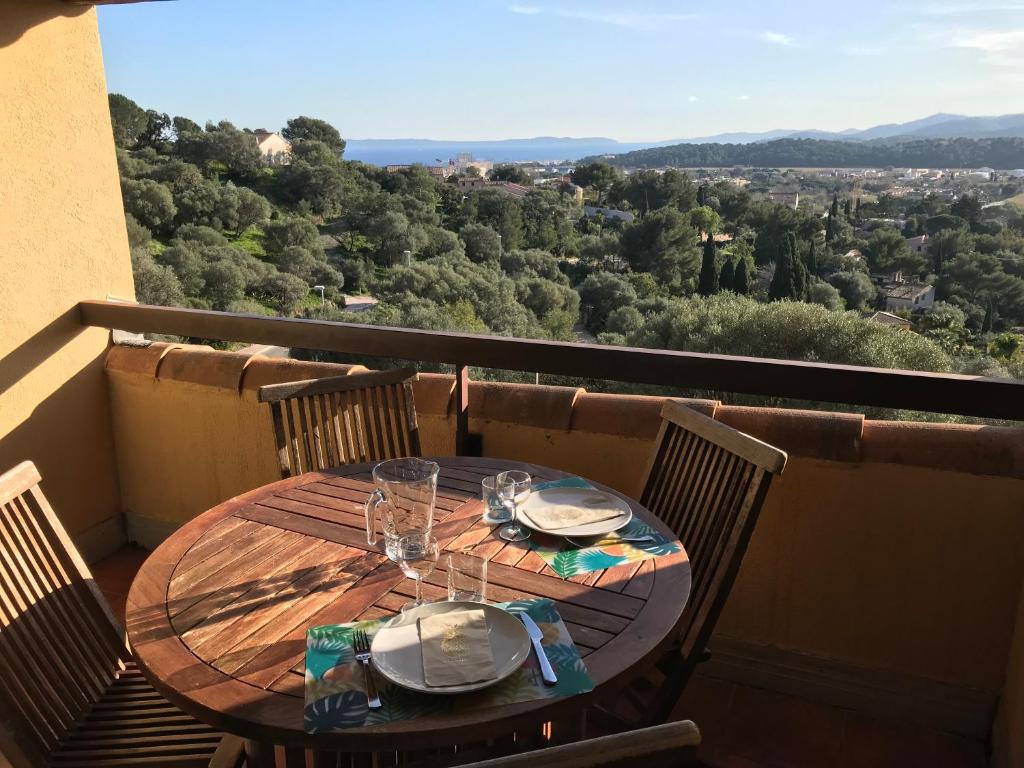 une table en bois avec des assiettes et des verres sur un balcon dans l'établissement Résidence Les Terrasses du Mirage - Duplex vue mer, à Bormes-les-Mimosas